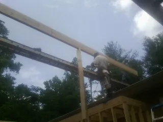 Carpenter setting a ridge beam over a new addition frame — Ice Dam Removal by Roofing Brothers in Bridgehampton
