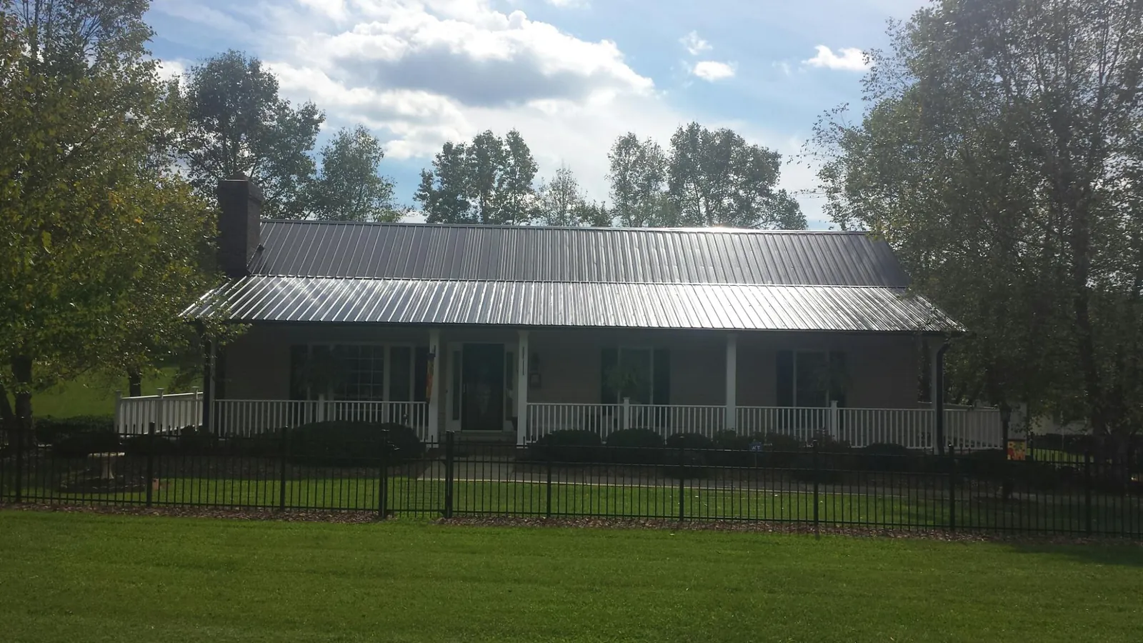 Gray metal roof on a brick ranch with a full width front porch — Gutter Guard Installation work by our crew in Bridgehampton